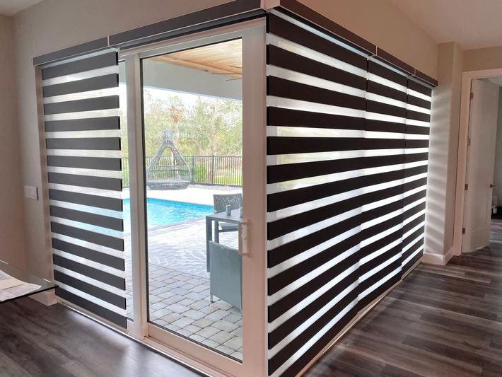 A room with a sliding glass door and blinds on it.