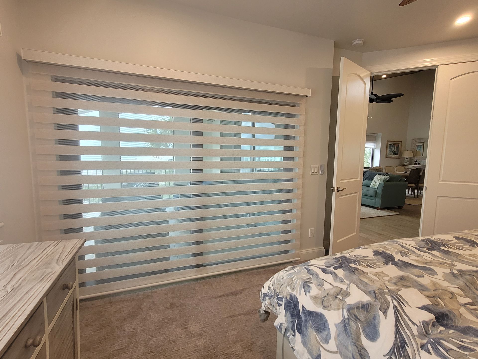 A bedroom with a bed and a sliding glass door with blinds on it.