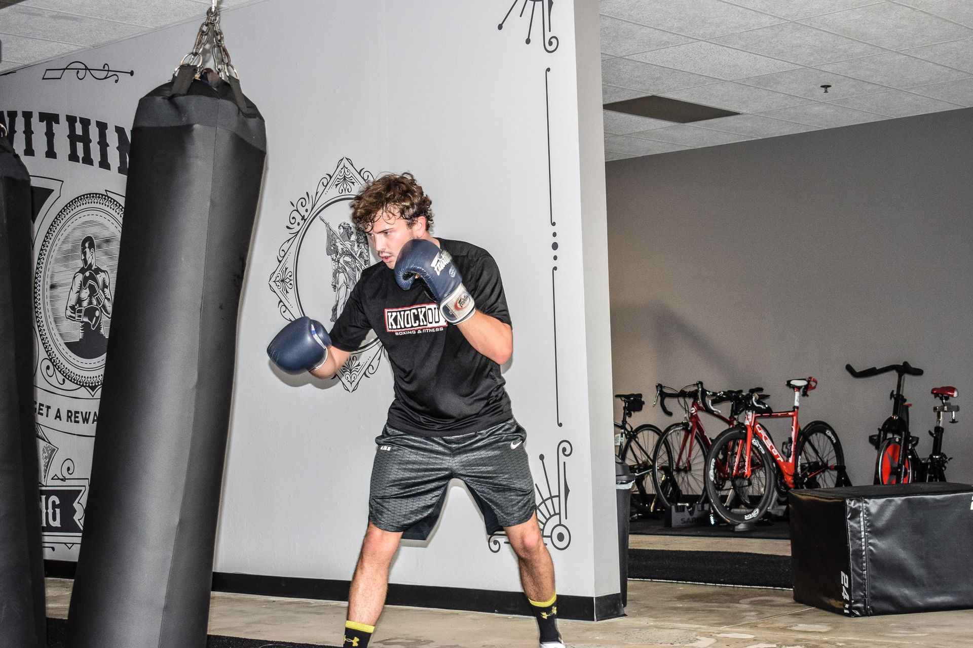 Man in boxing gloves punching a heavy bag in a gym.