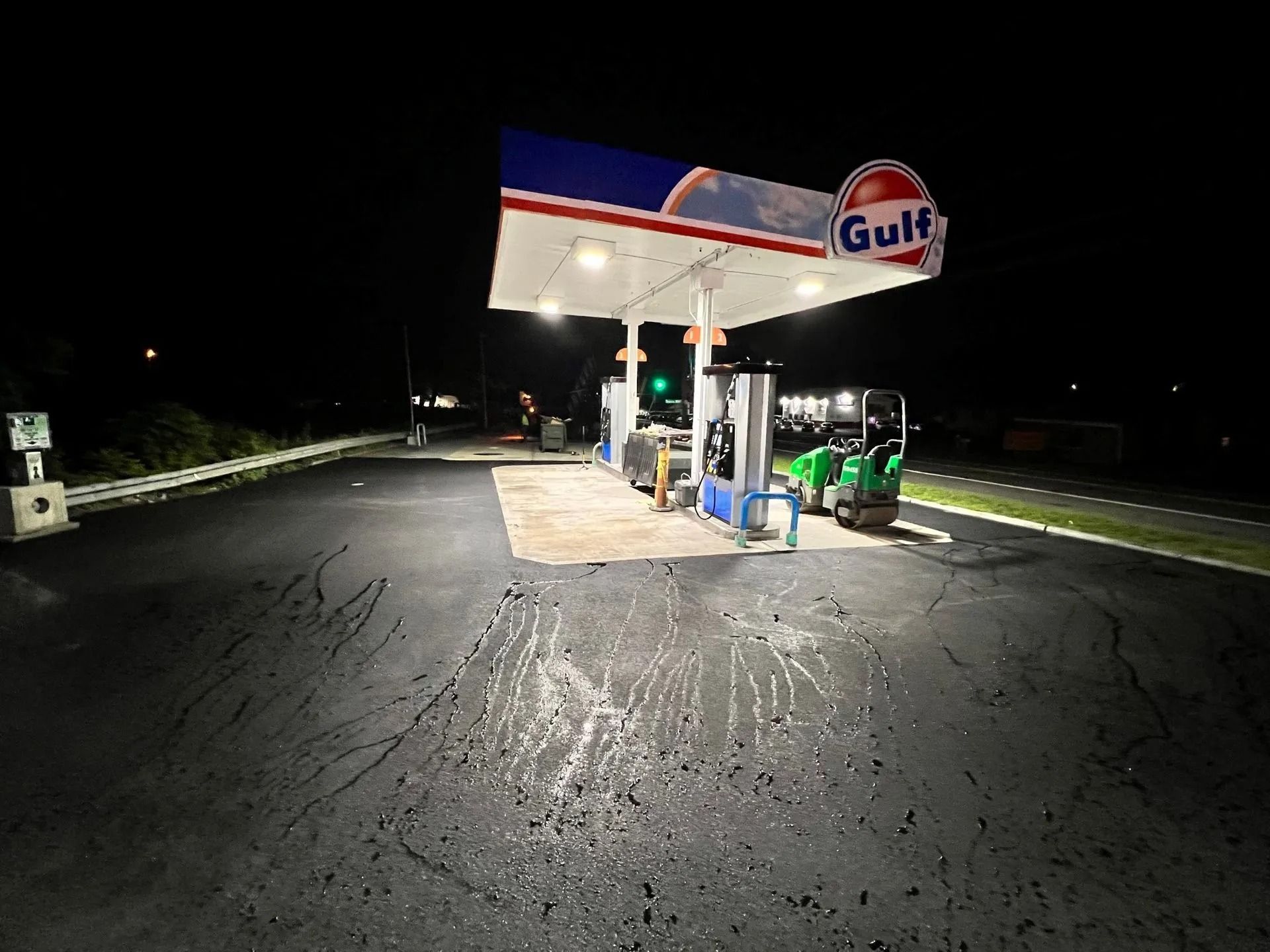 A Gulf gas station at night, featuring illuminated pump islands and a newly paved asphalt surface.