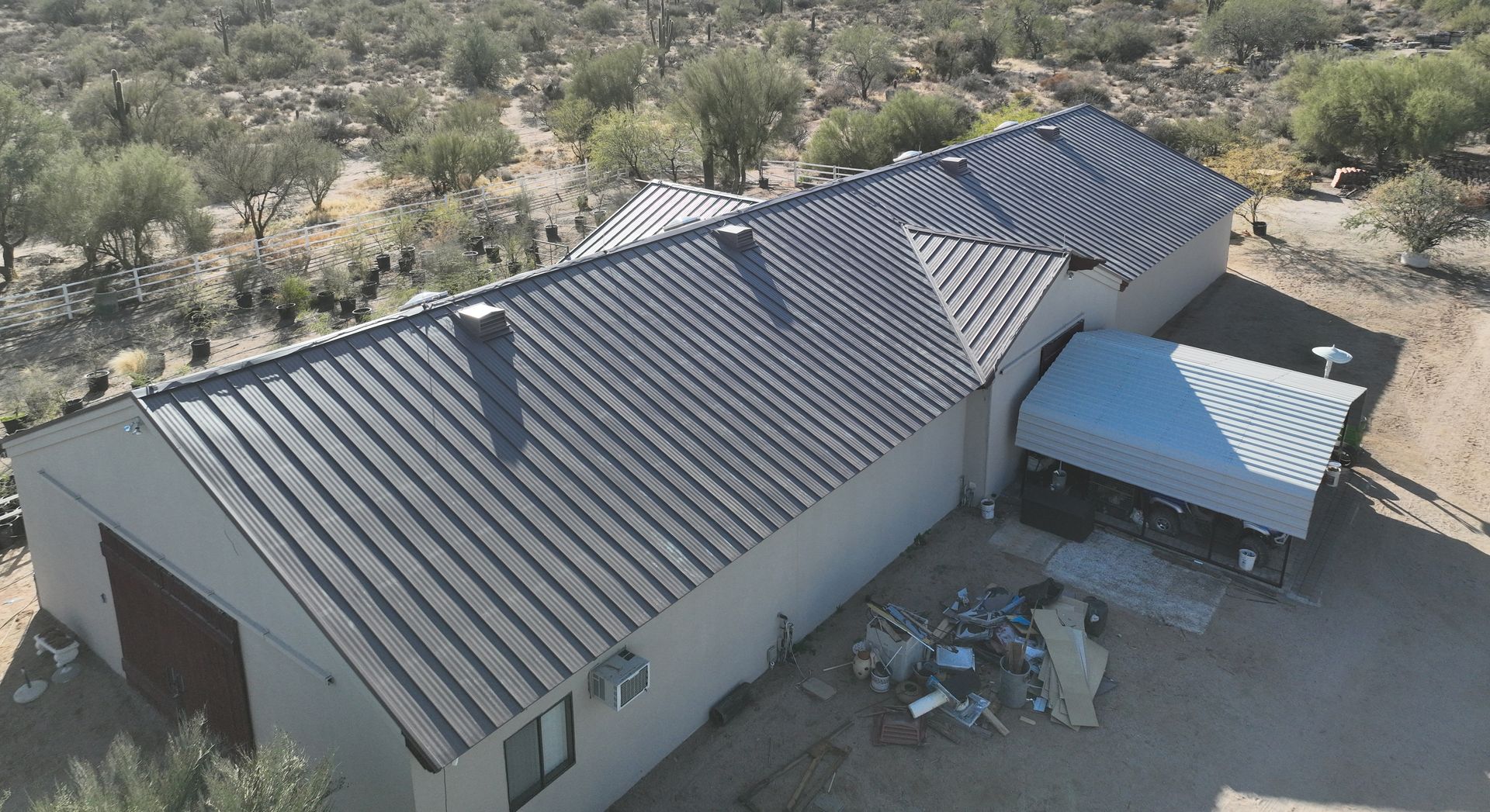 An aerial view of a house with a metal roof in the desert.