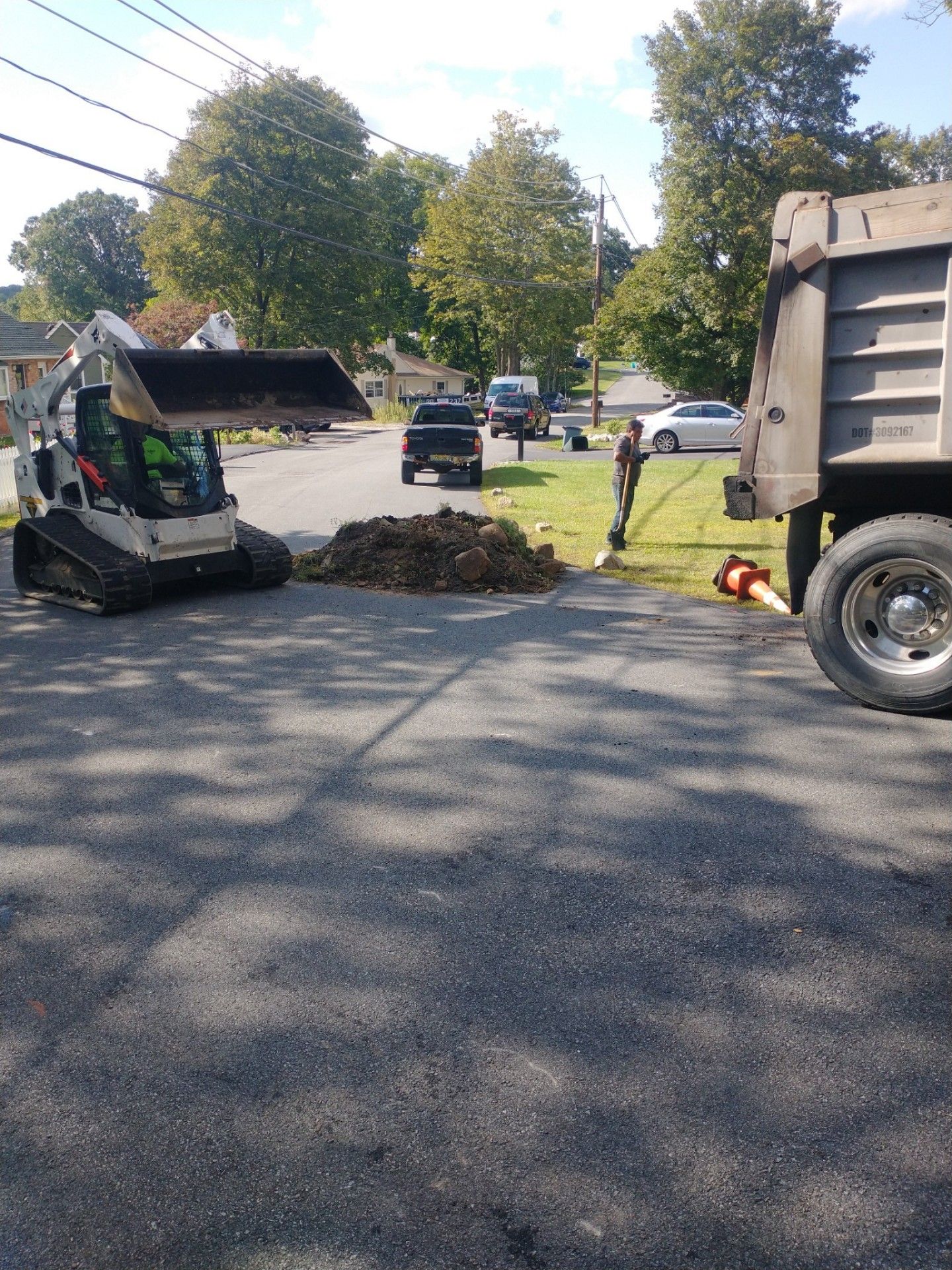A bulldozer is driving down a street next to a dump truck.