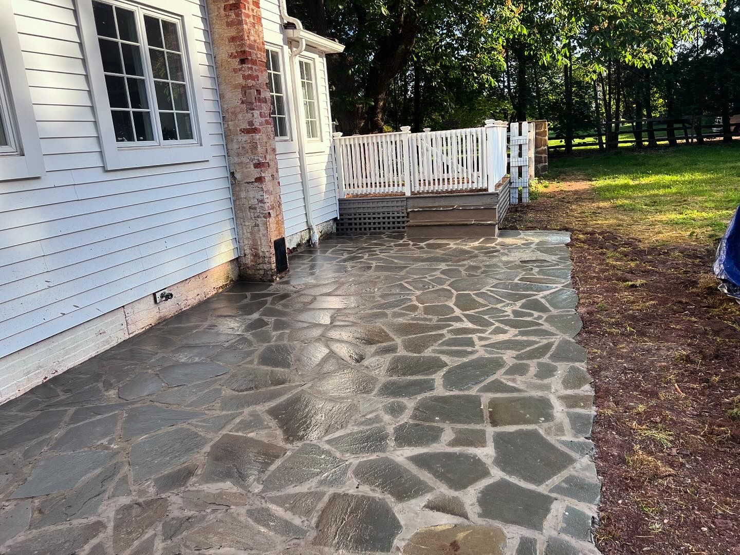 A stone walkway leading to a white house with a white fence.