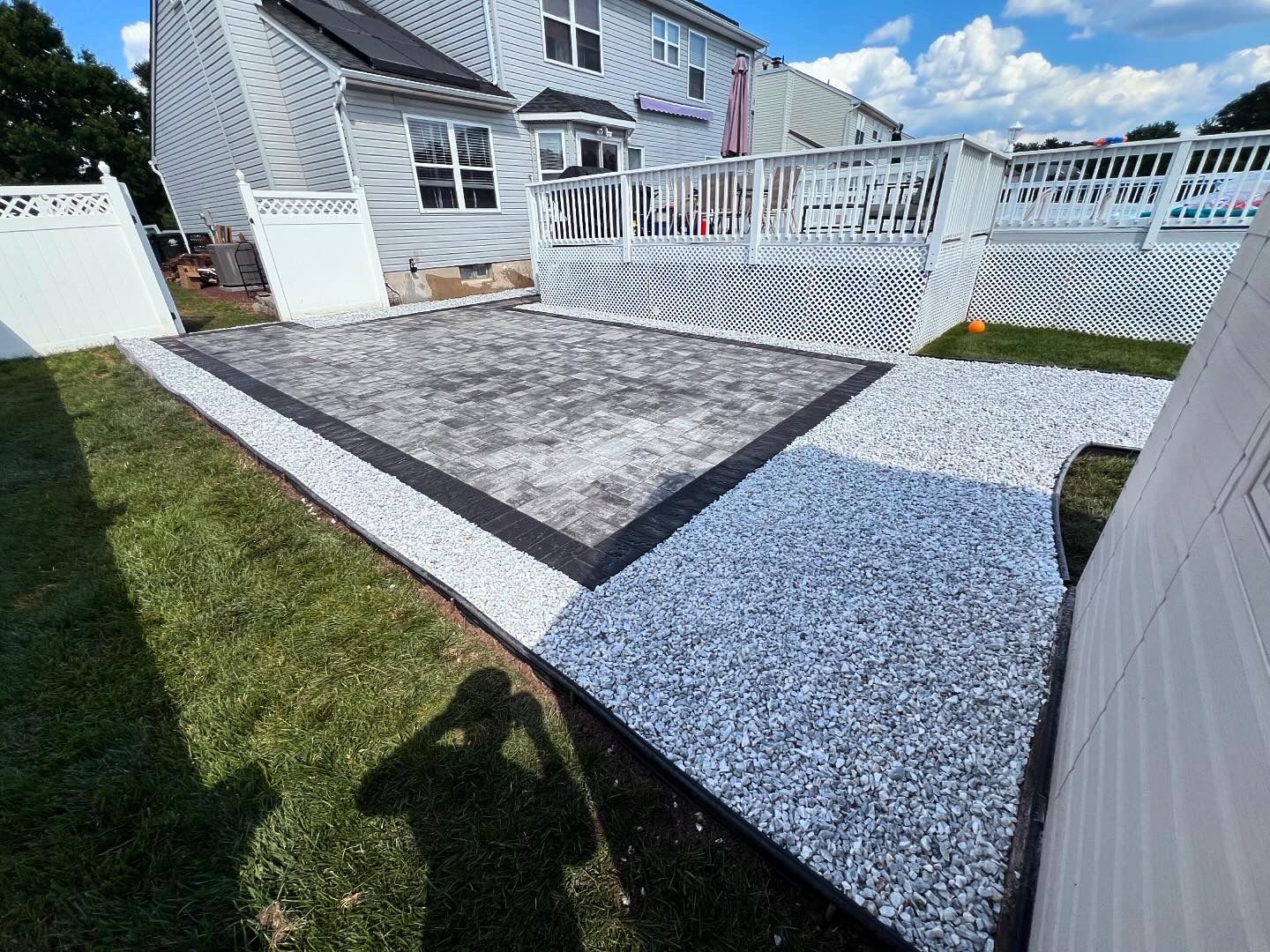 A patio with a white fence and a white house in the background.
