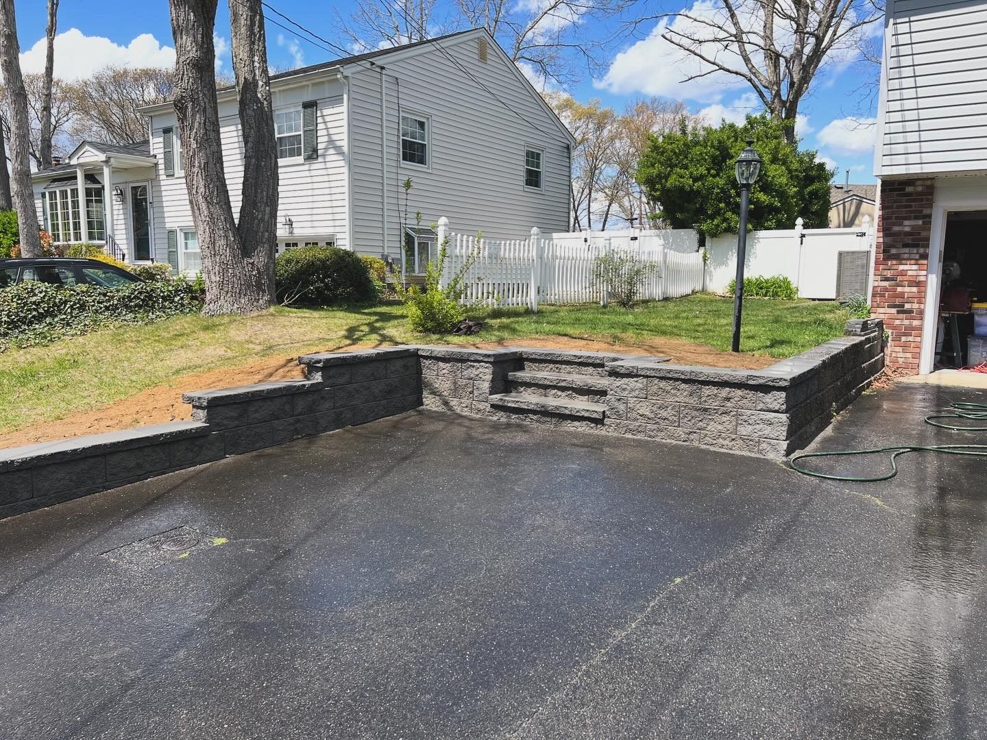 A driveway with a stone wall and steps in front of a house.