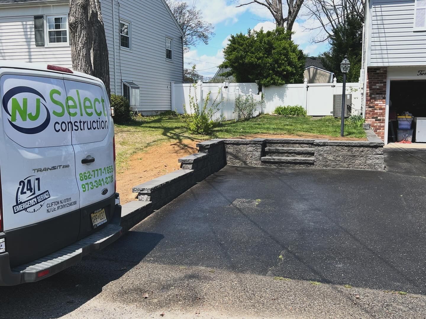 A nj select construction van is parked in front of a house