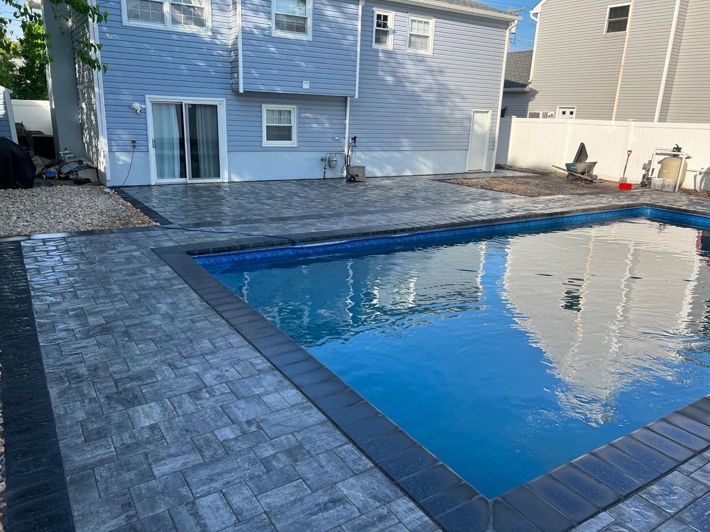 A large swimming pool is in the backyard of a house.