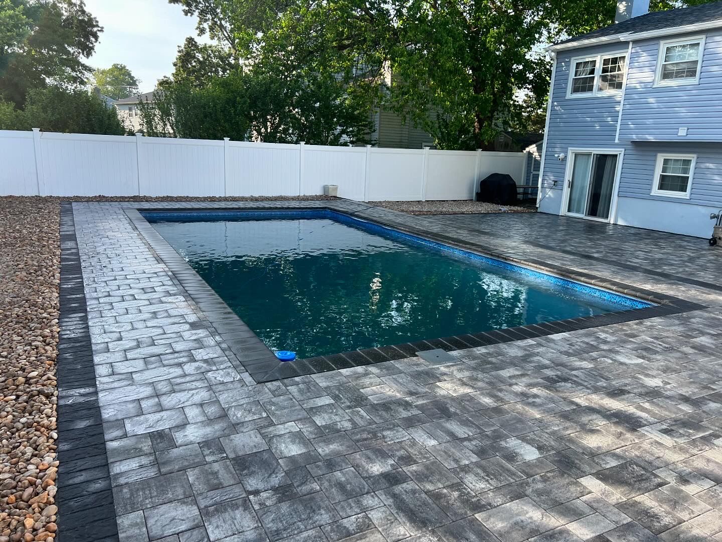 There is a large swimming pool in the backyard of a house.