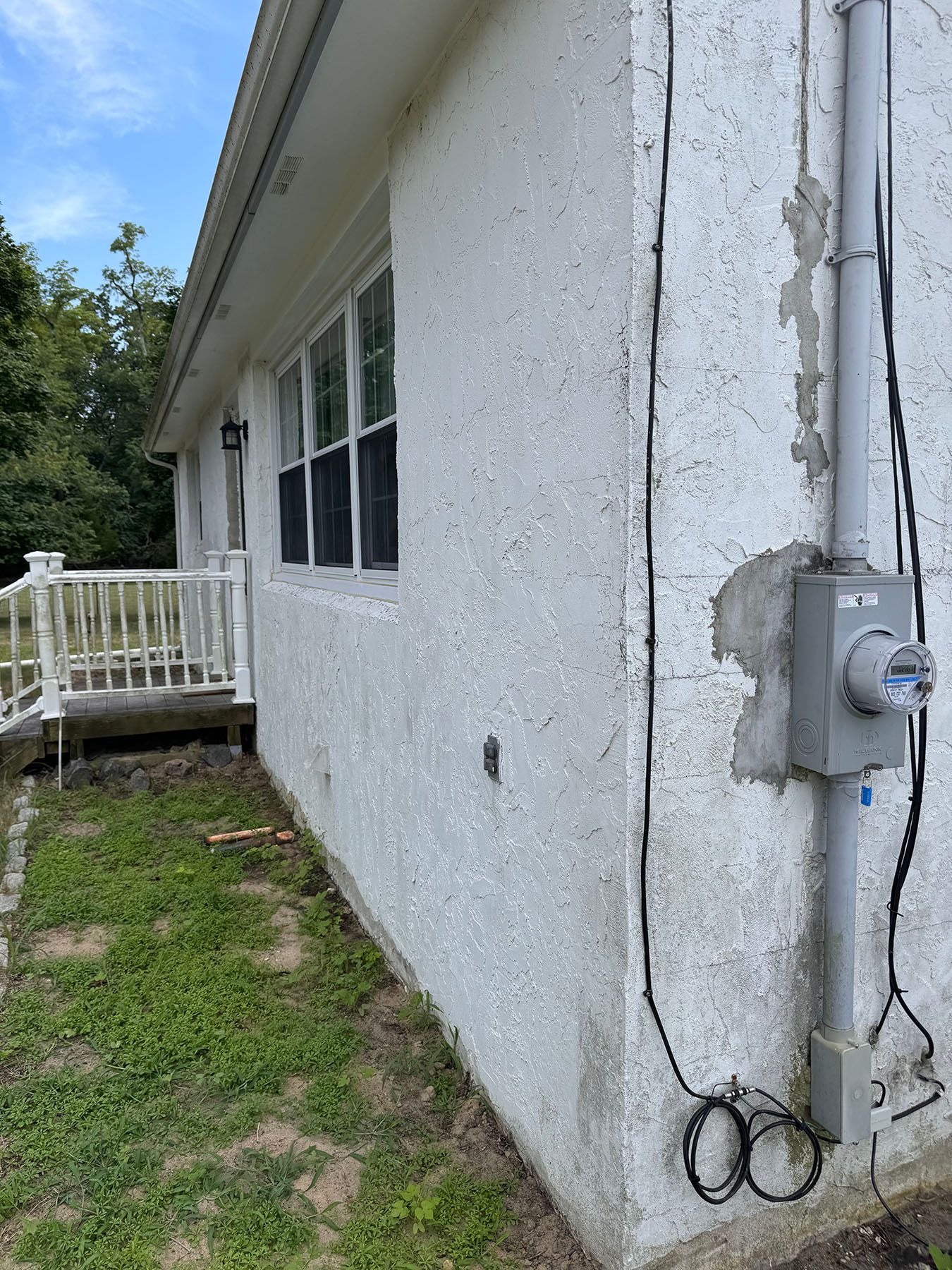 A white house with a electrical box on the side of it.