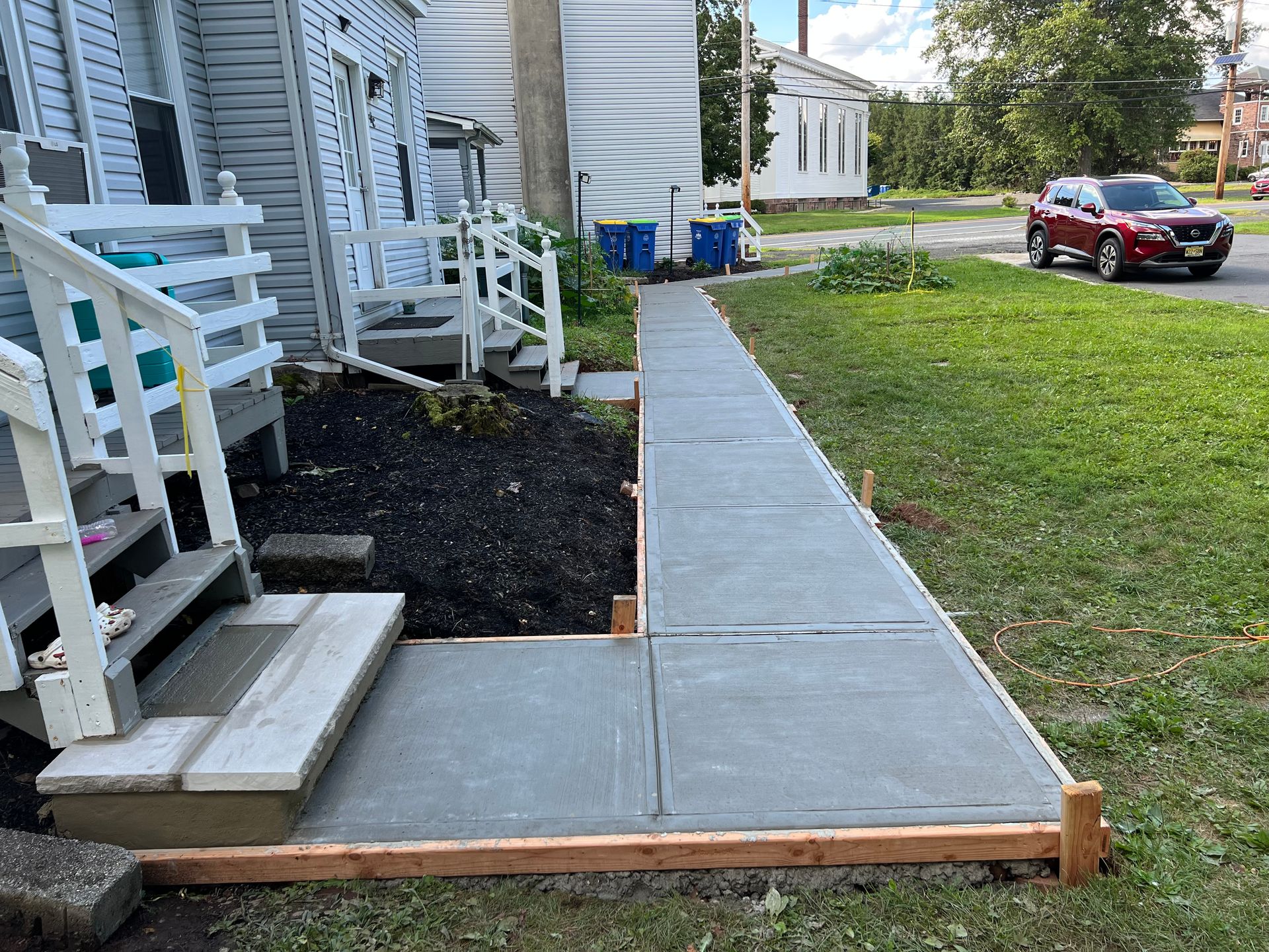 A concrete walkway is being built in front of a house.