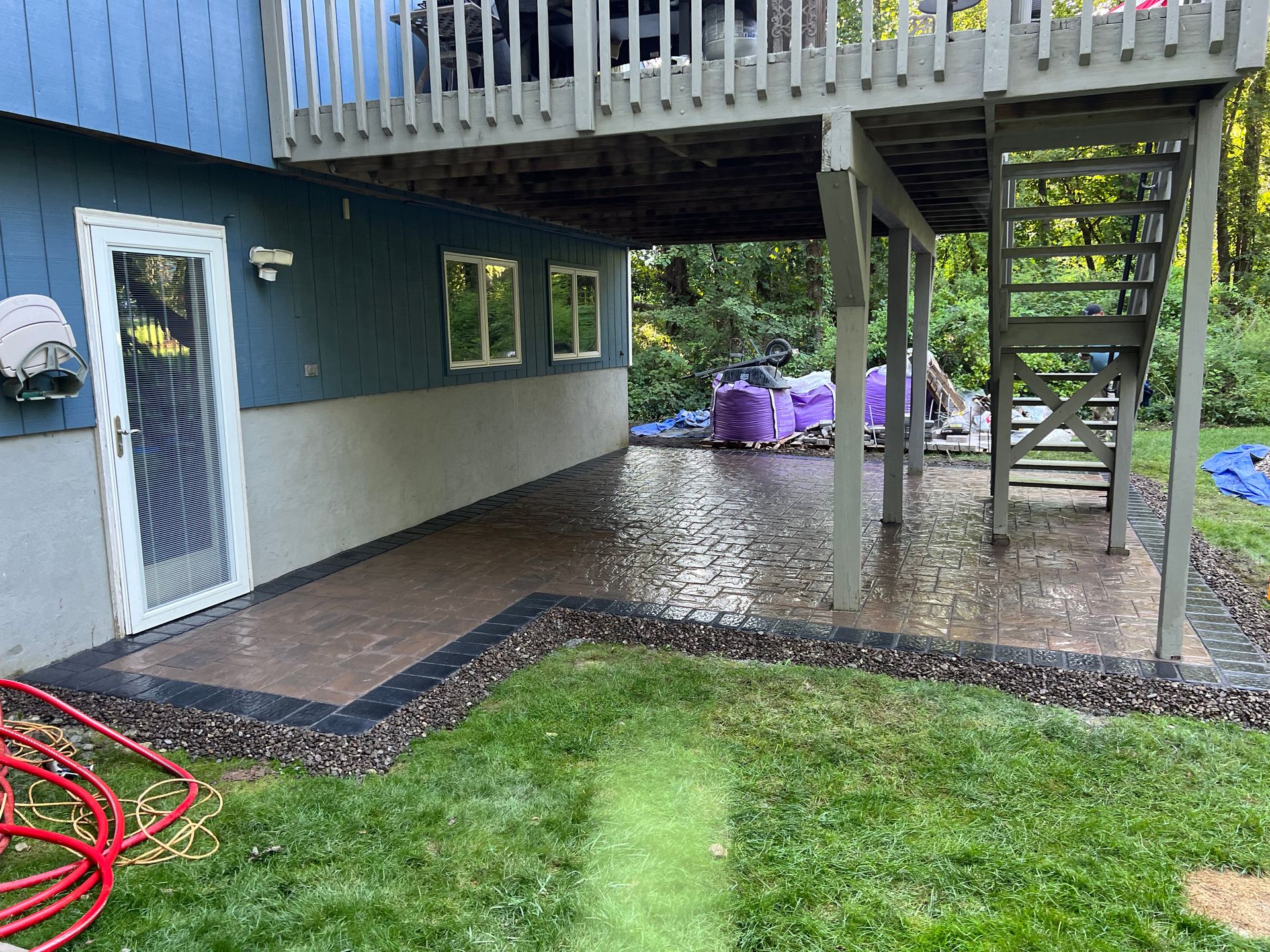 A patio with a deck and stairs in the backyard of a house.