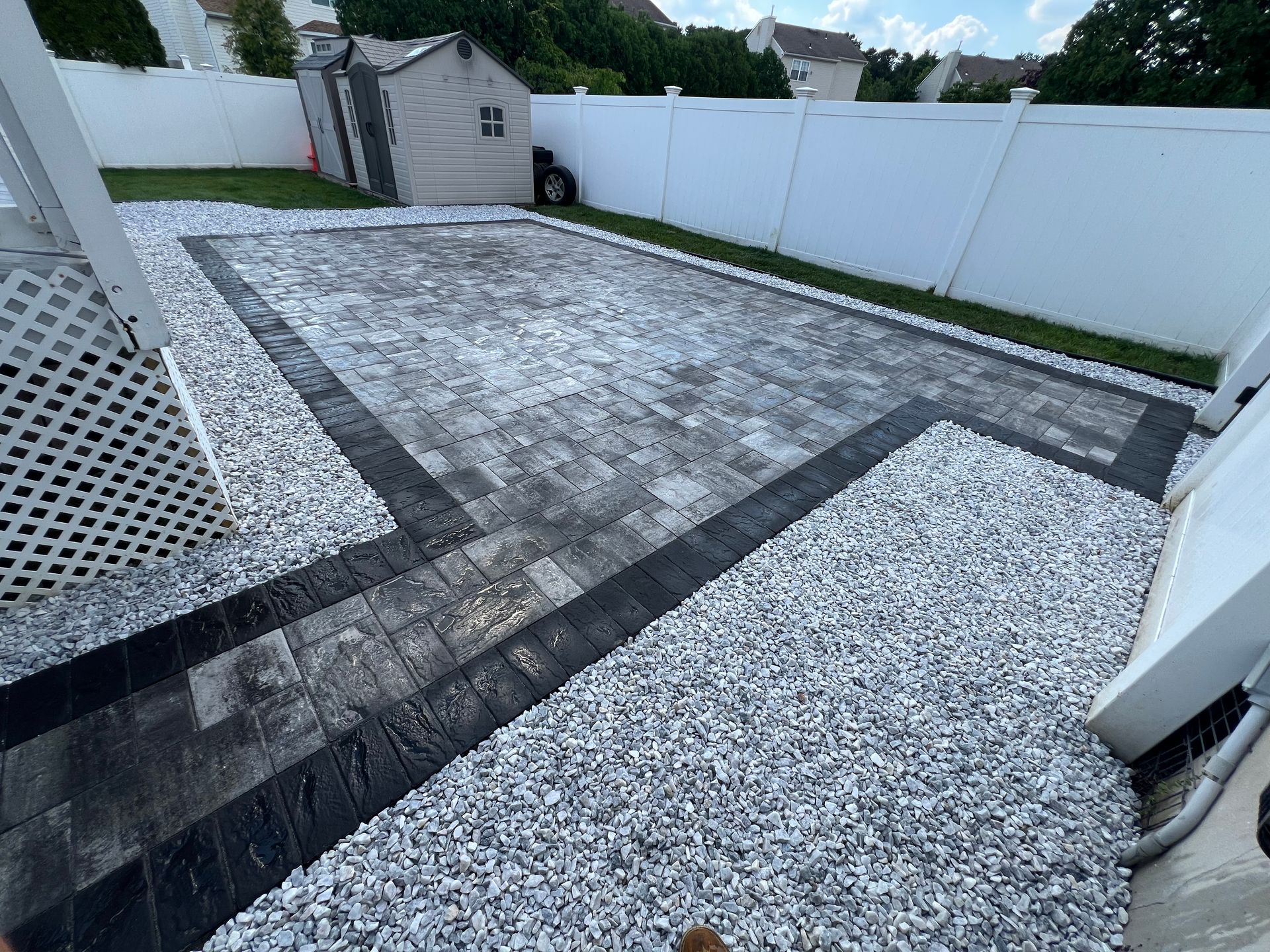 A patio with a white fence and a shed in the background.