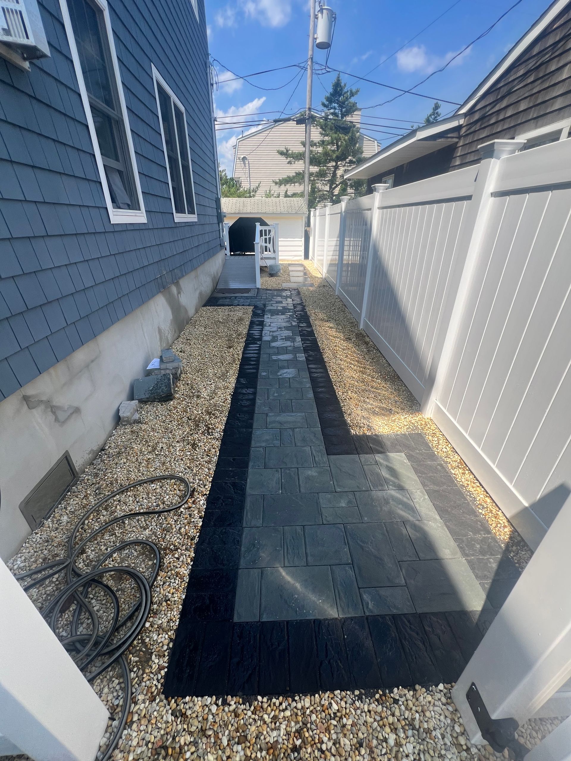 A walkway between two houses with a white fence.
