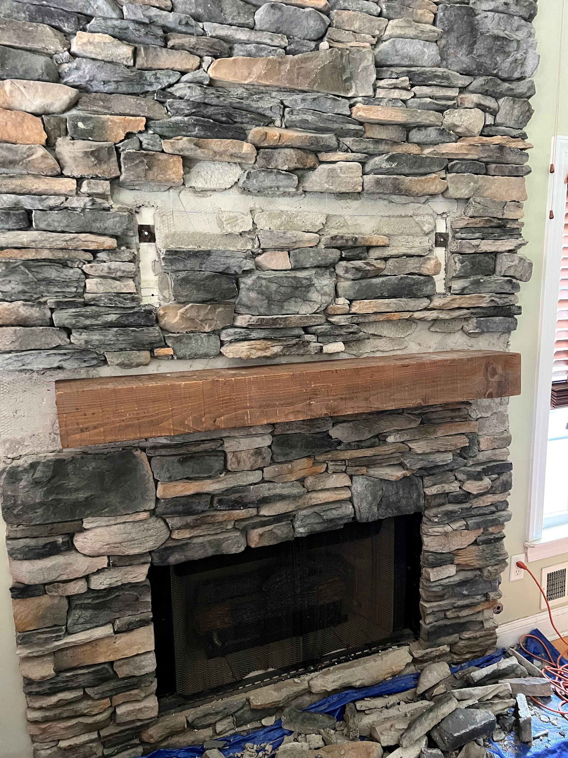 A stone fireplace is being remodeled in a living room.