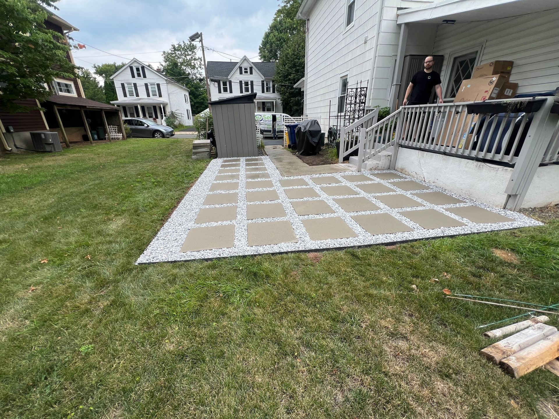 A man is standing on a patio in front of a house.