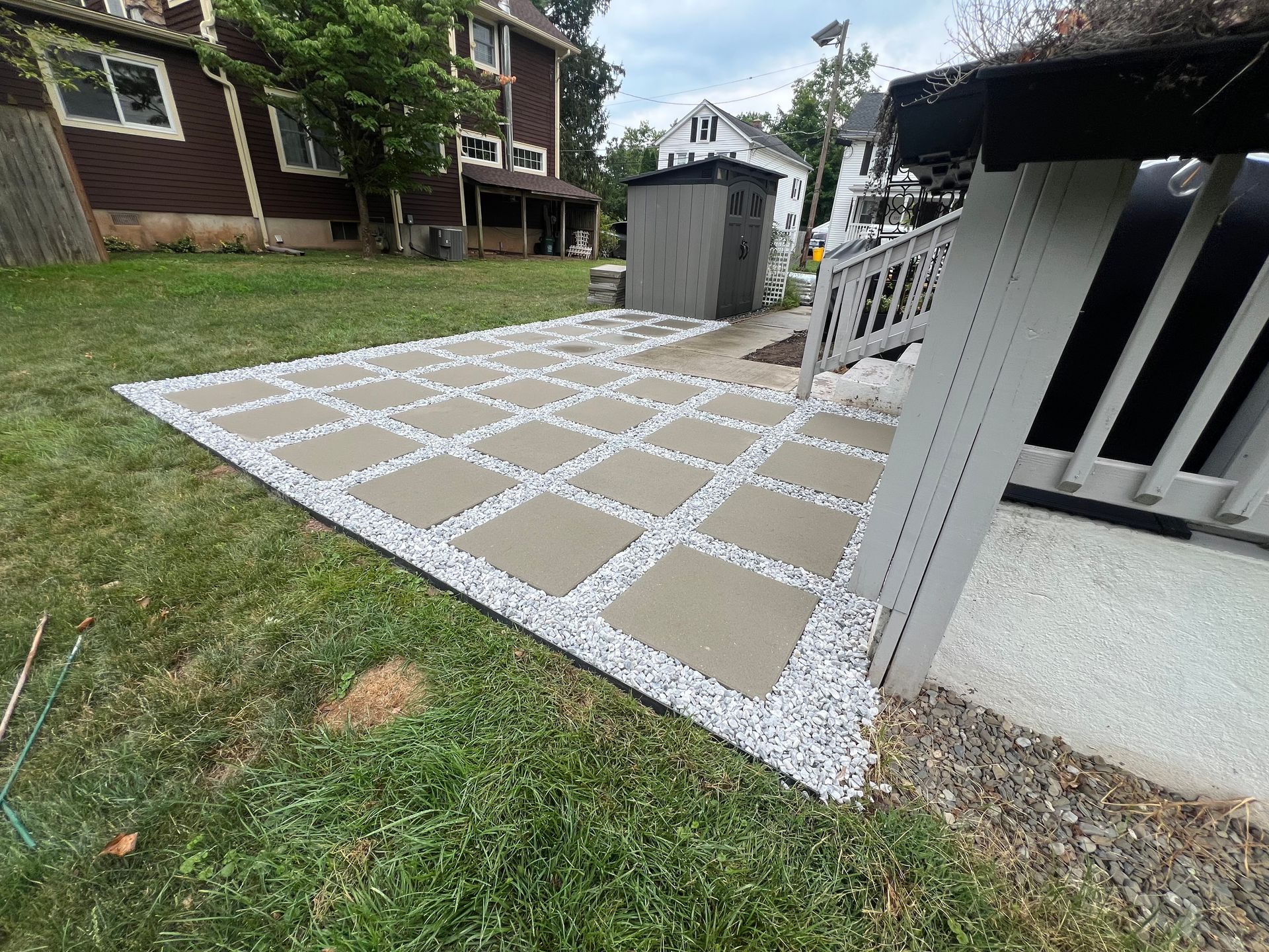 A patio with concrete tiles and gravel in front of a house.