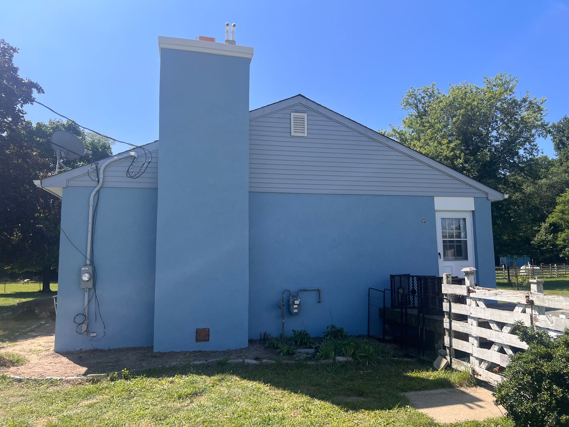A blue house with a chimney on the side of it