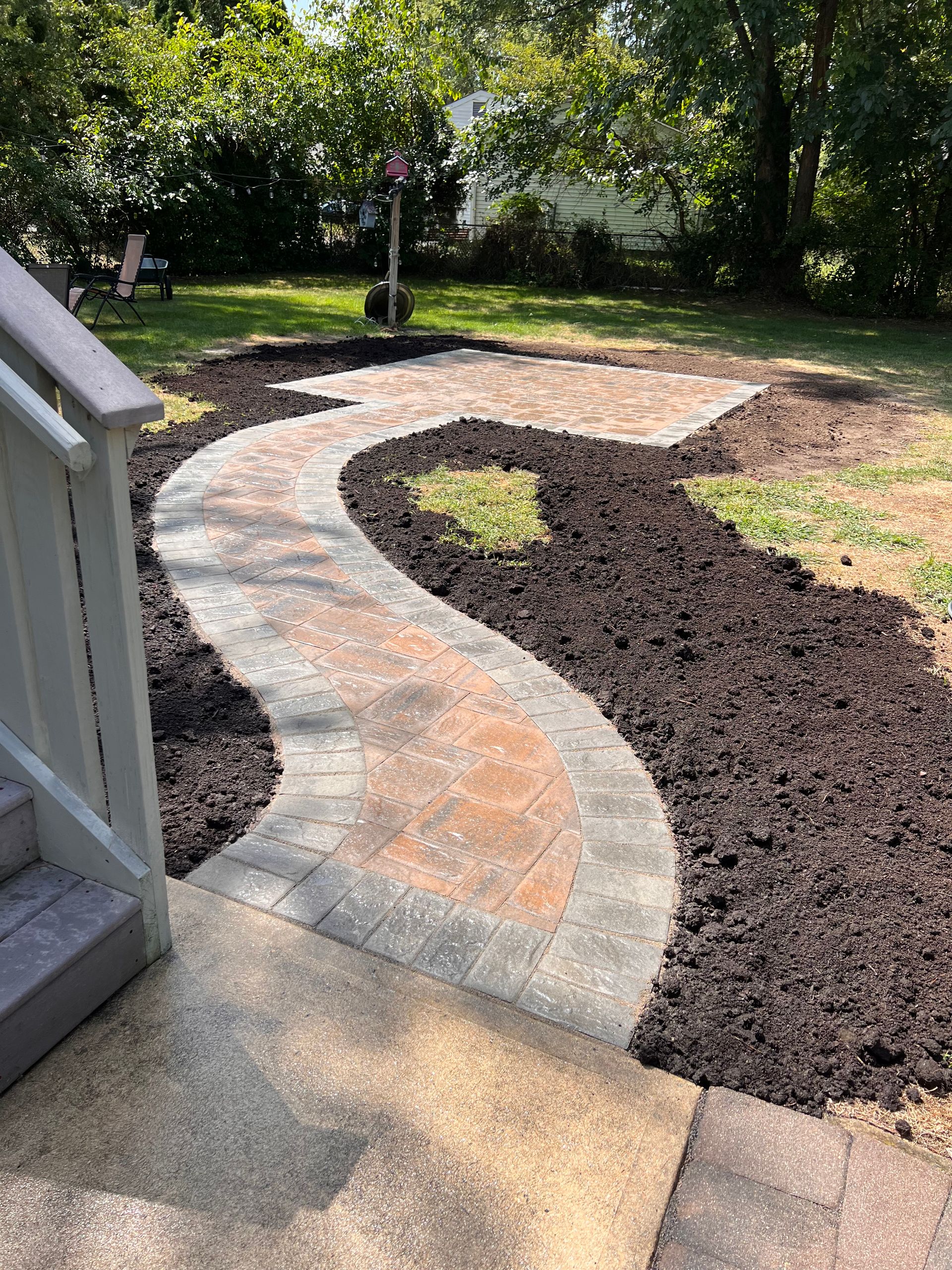 A walkway is being built in the backyard of a house.