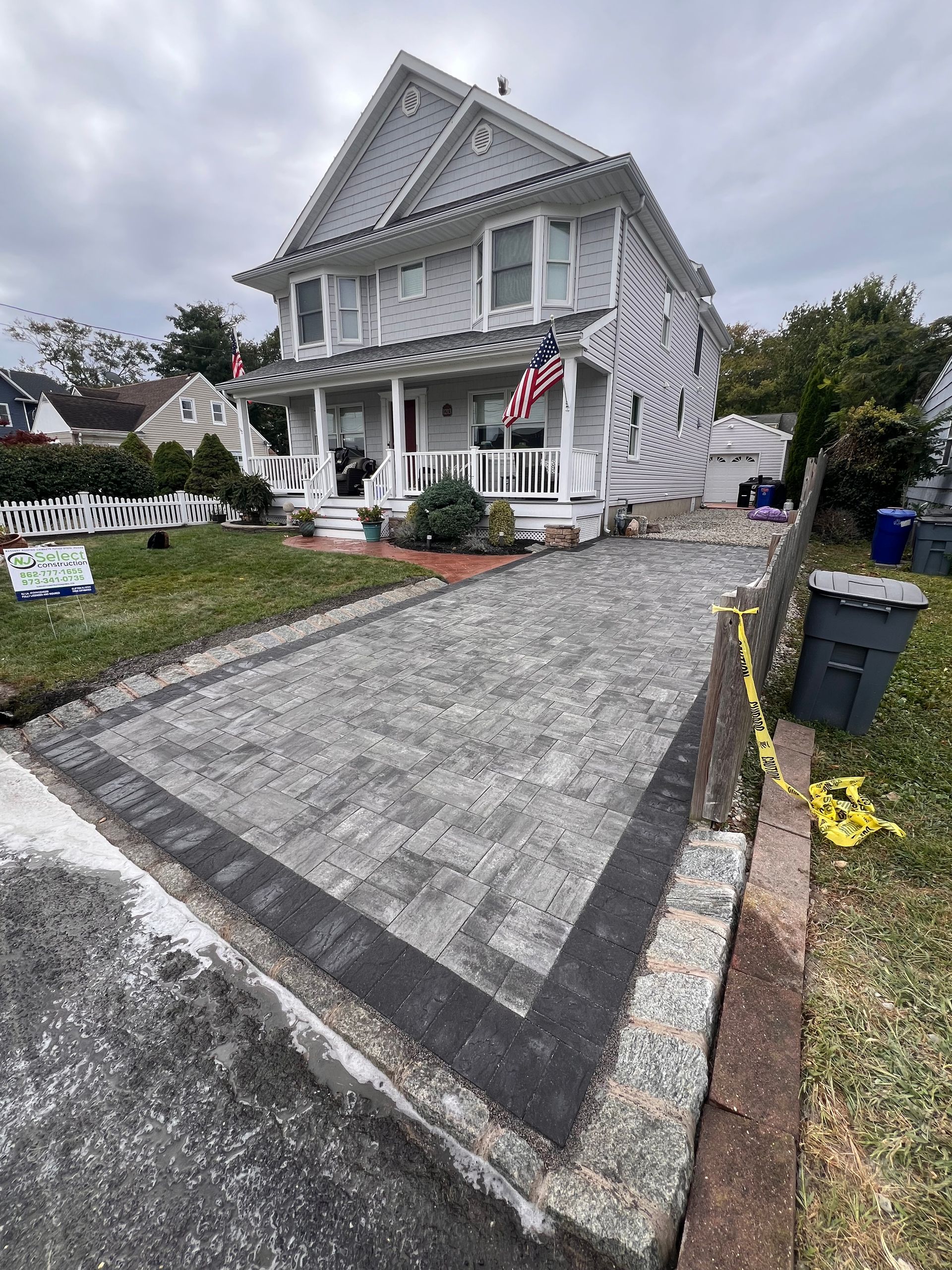 A large white house with a brick driveway in front of it.