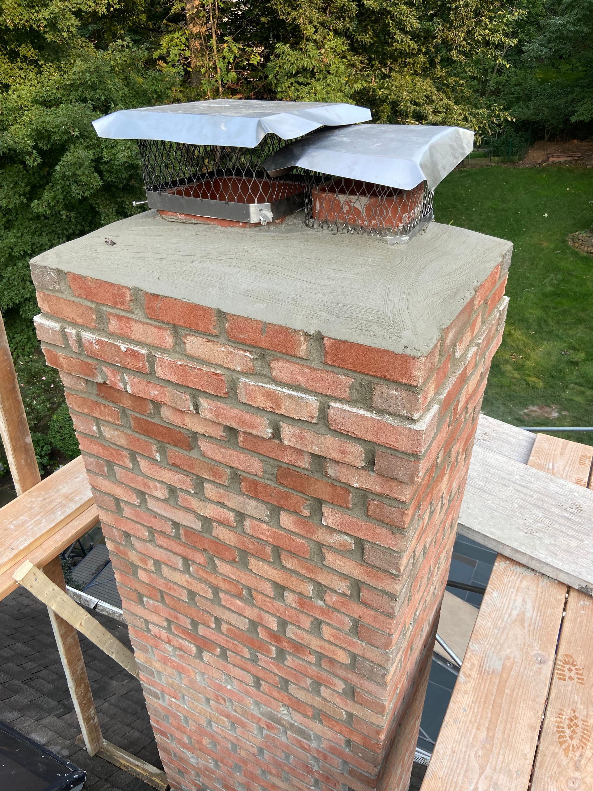 A brick chimney is sitting on top of a wooden scaffolding.