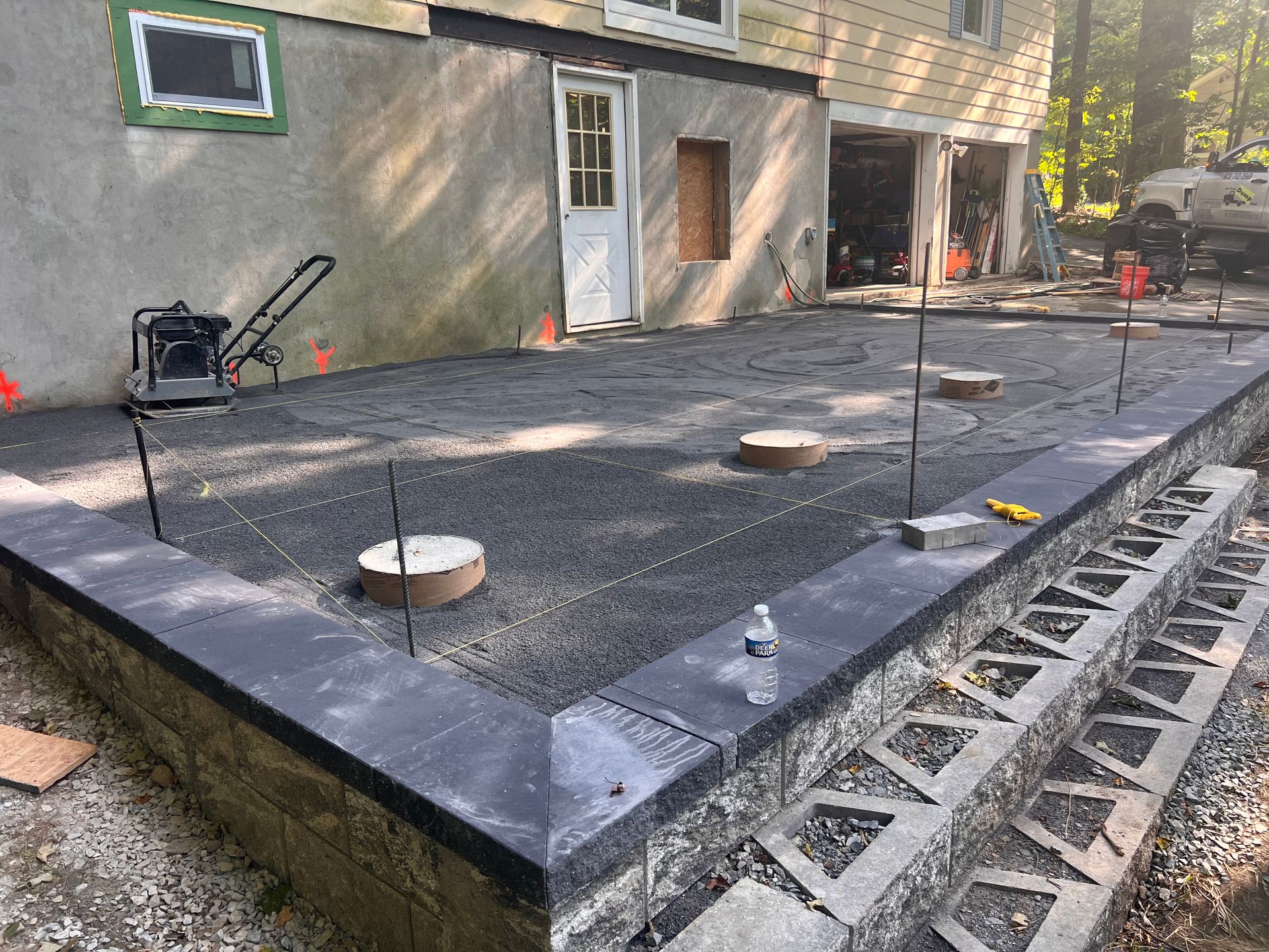 A concrete patio is being built in front of a house.