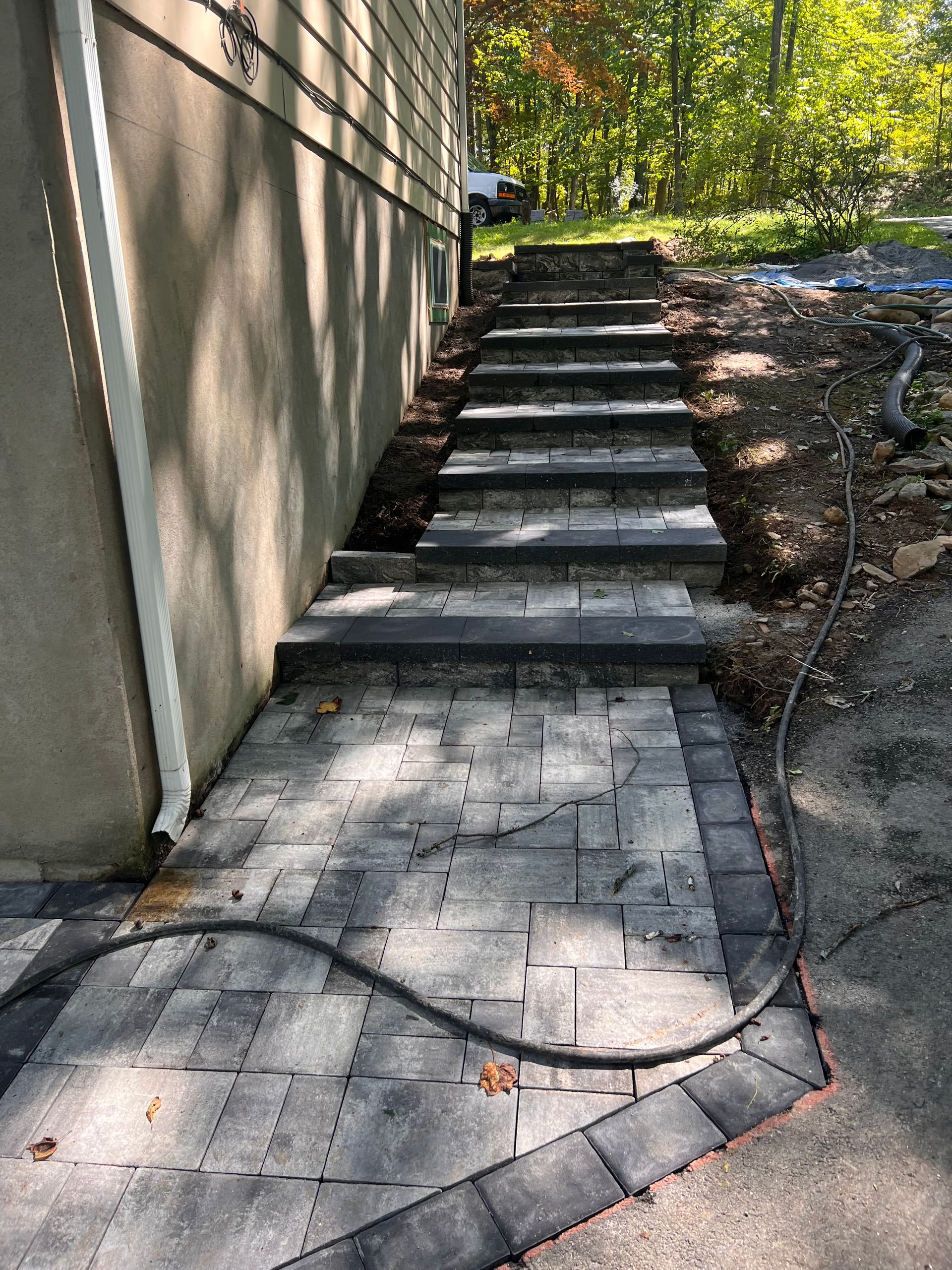 A hose is connected to a brick walkway leading to a house.
