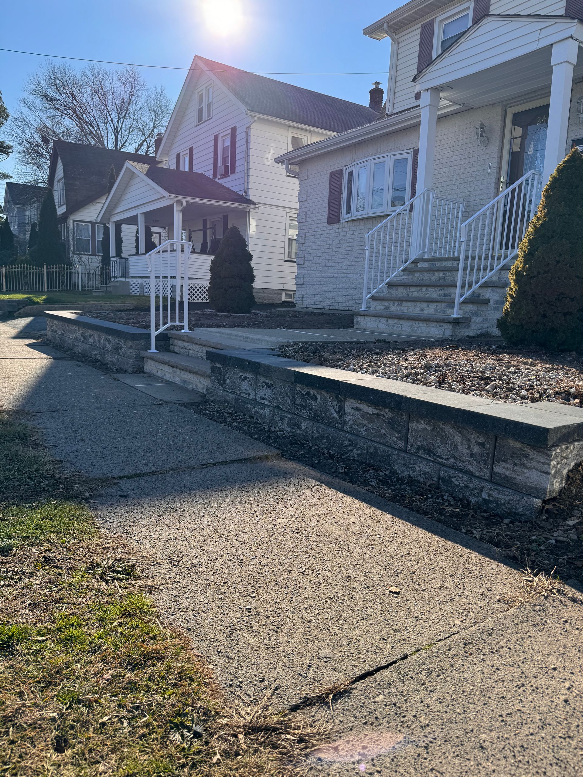 A row of houses with stairs and a stone wall in front of them.
