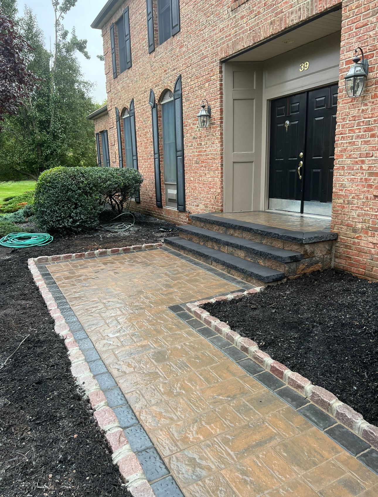 A brick house with a brick walkway leading to the front door.