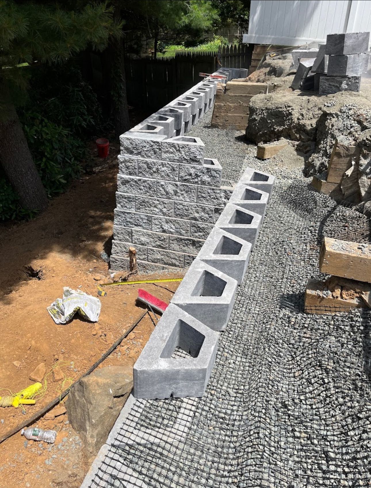A brick wall is being built in a backyard.