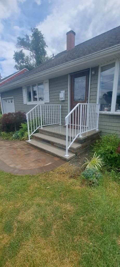 A house with a white railing and stairs in front of it.
