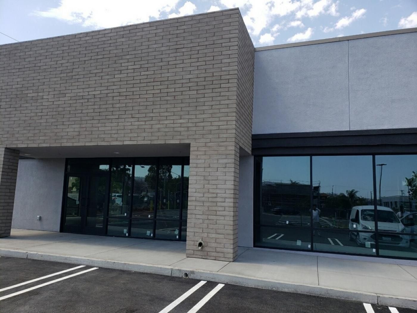 Exterior of a modern commercial building with large glass windows and light-colored brick facade.