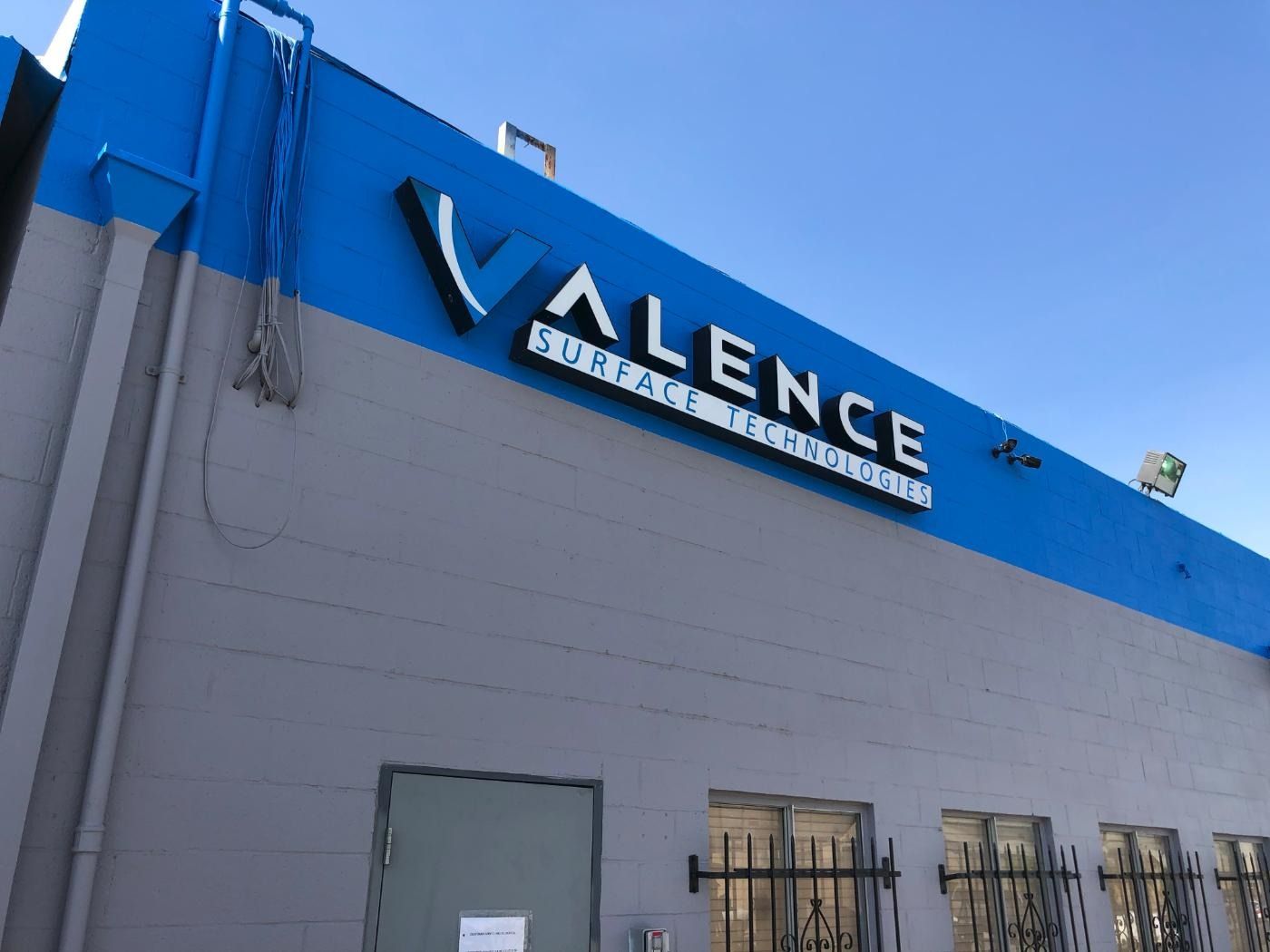 Building with a blue and gray facade; sign reads 