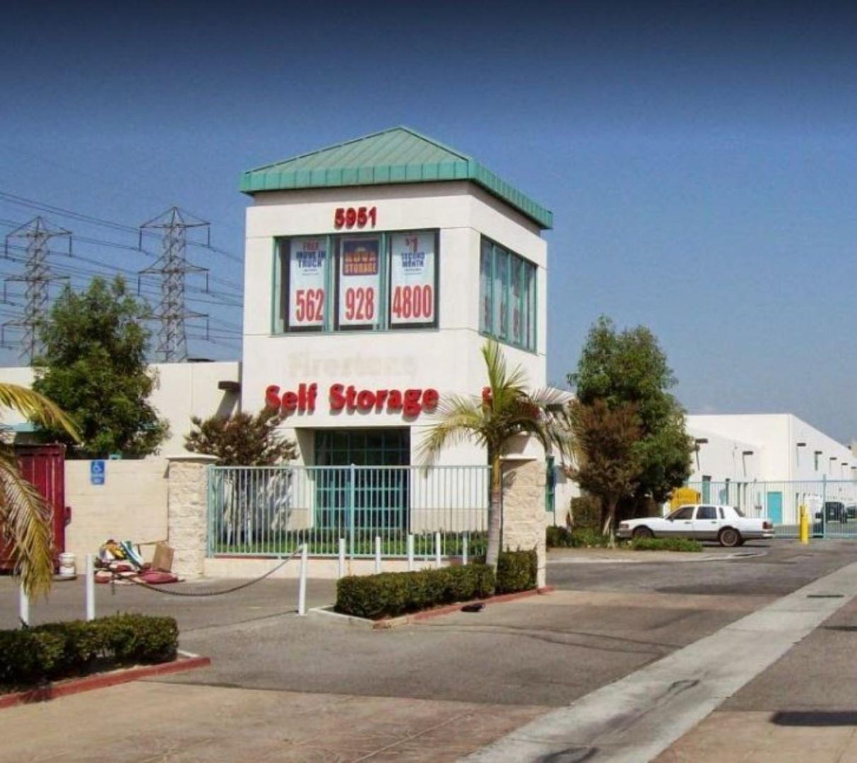 Self Storage building with tower; white facade, green roof, gated entrance.