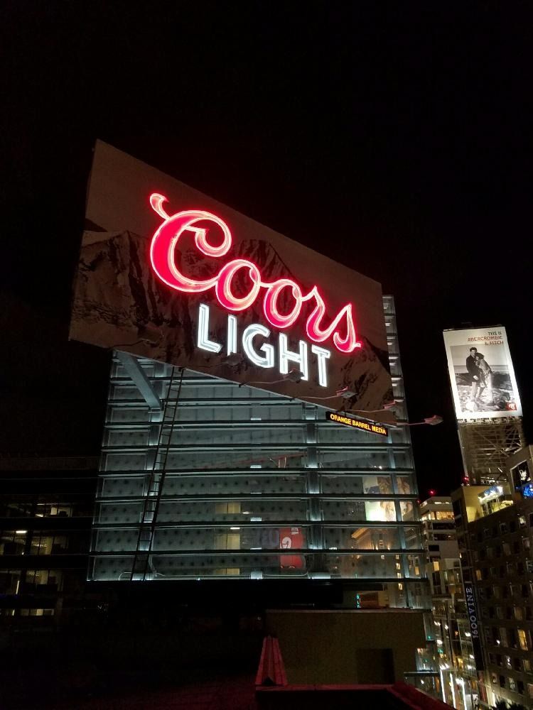 Coors Light neon sign atop a modern building at night.