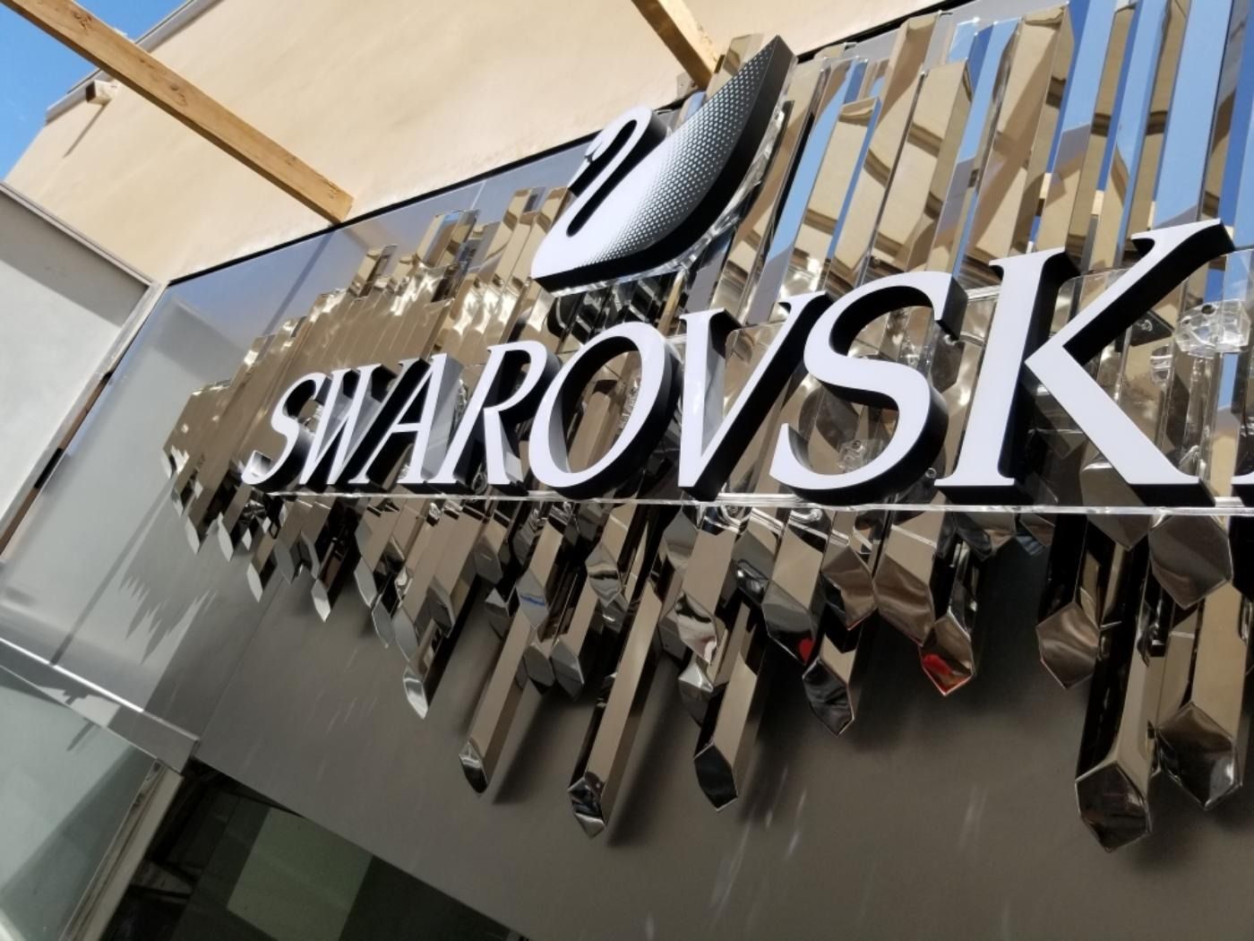 Swarovski store sign with reflective, geometric accents and the brand logo.