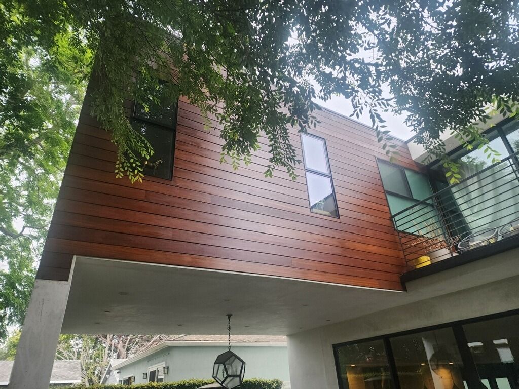Modern house with wood siding and large windows, viewed from below.