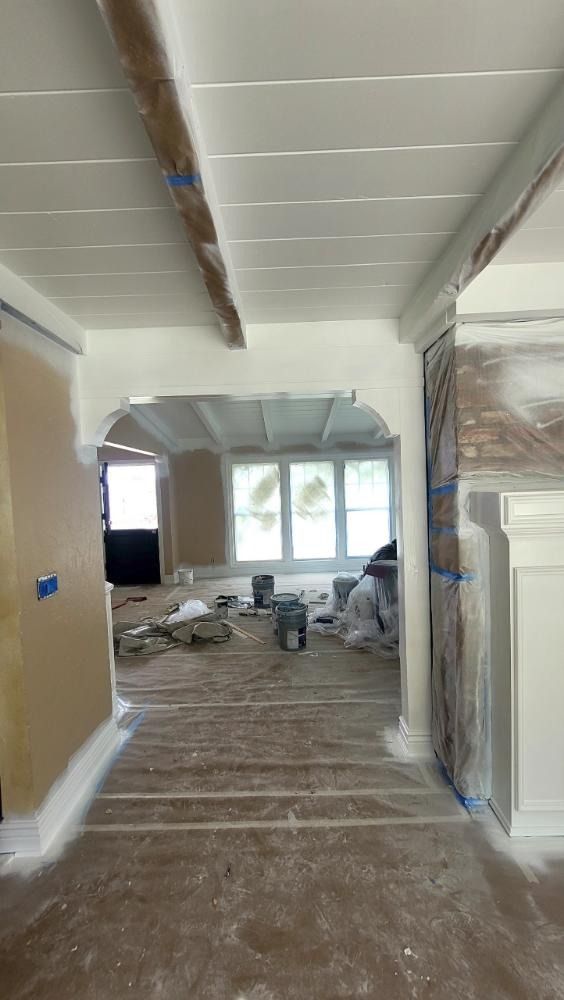 Interior of a house under renovation, with painted white beams, trim, and doorway.