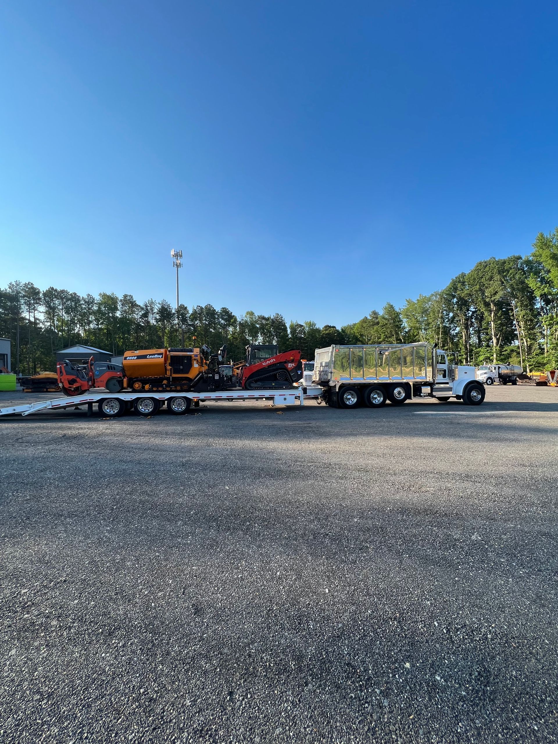 A semi truck with a trailer attached to it is parked in a gravel lot.