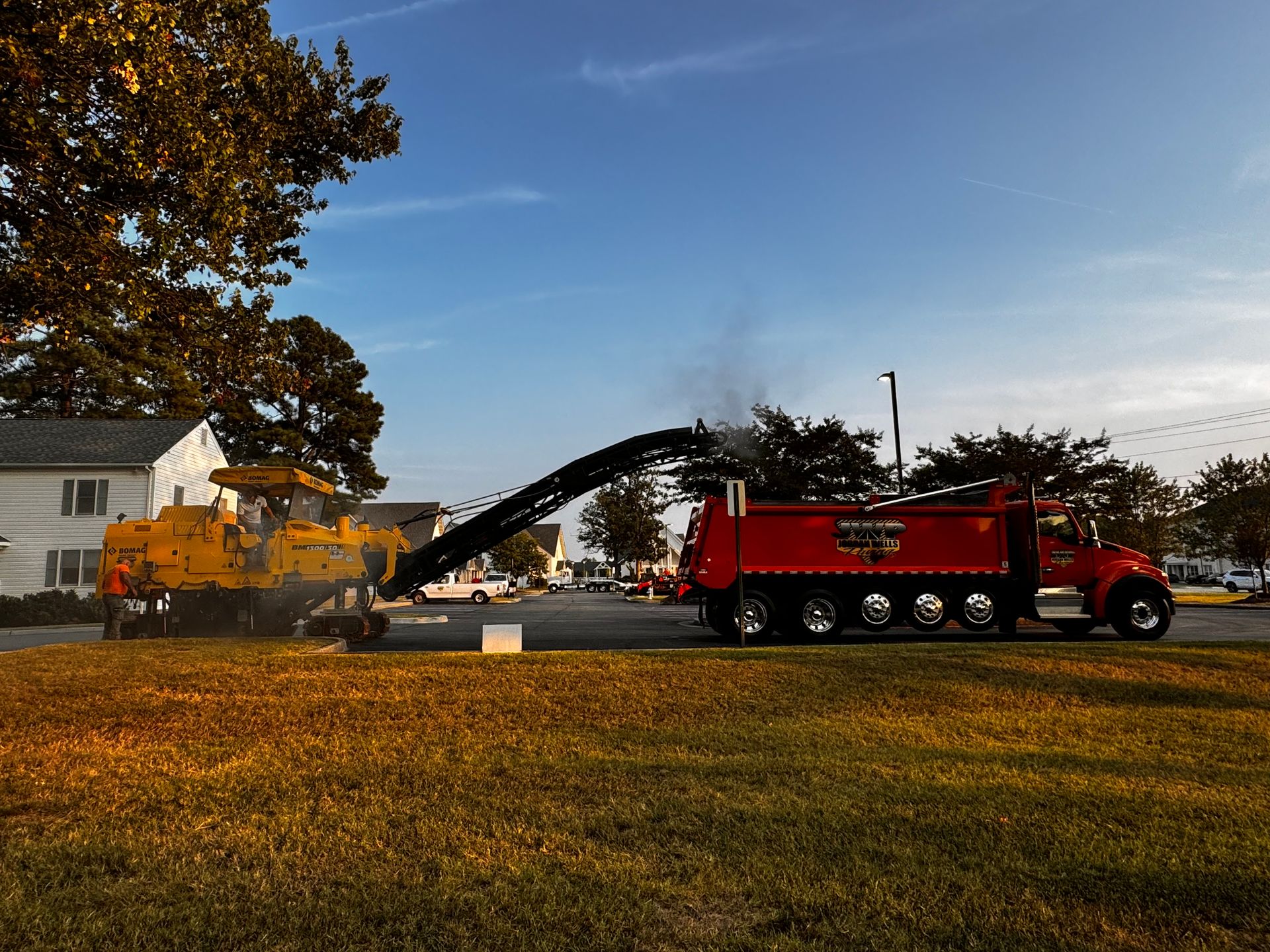 A red truck is driving down a street next to a yellow truck.