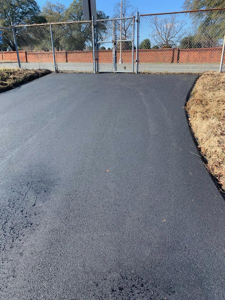 A black asphalt road with a fence in the background.