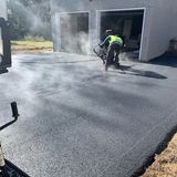 A man is paving a driveway in front of a garage.