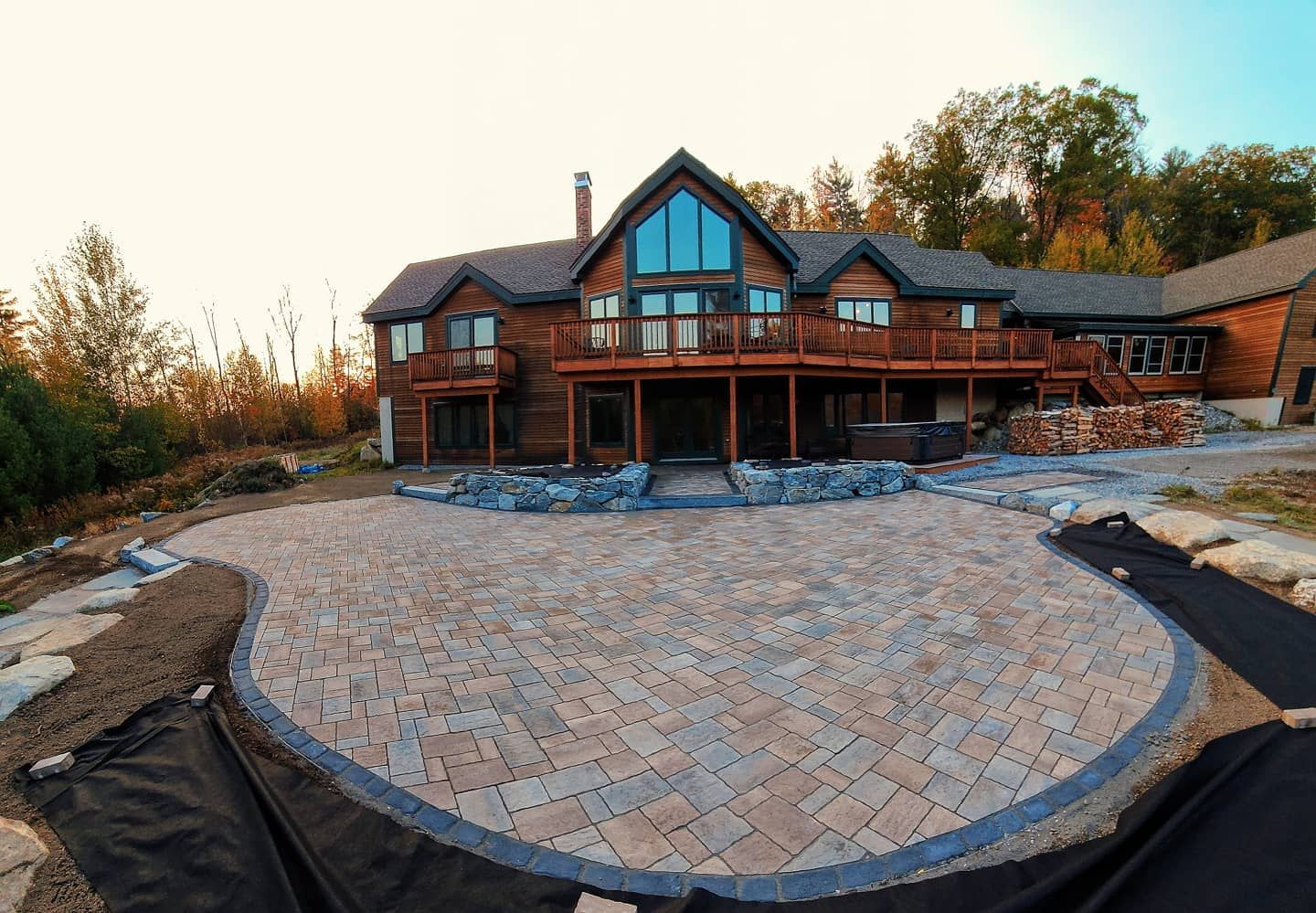 A log cabin home with a newly paved patio, with a herringbone pattern and decorative border.