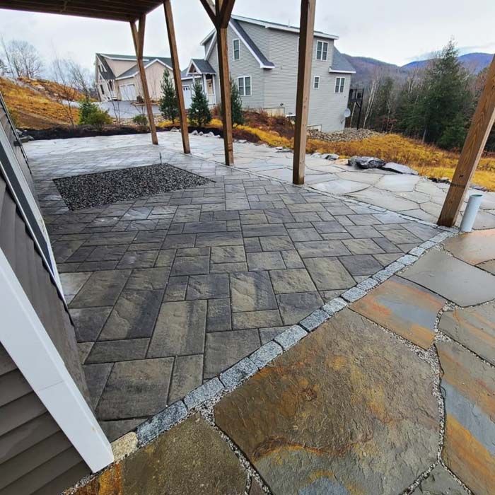 Stone patio with a mix of rectangular and irregular flagstones, under a wooden deck.