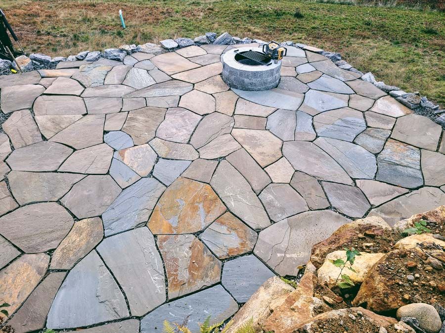 Stone patio with fire pit; various irregular-shaped stones in neutral tones.
