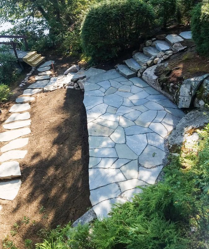 Stone pathways and steps through a landscaped garden with greenery.