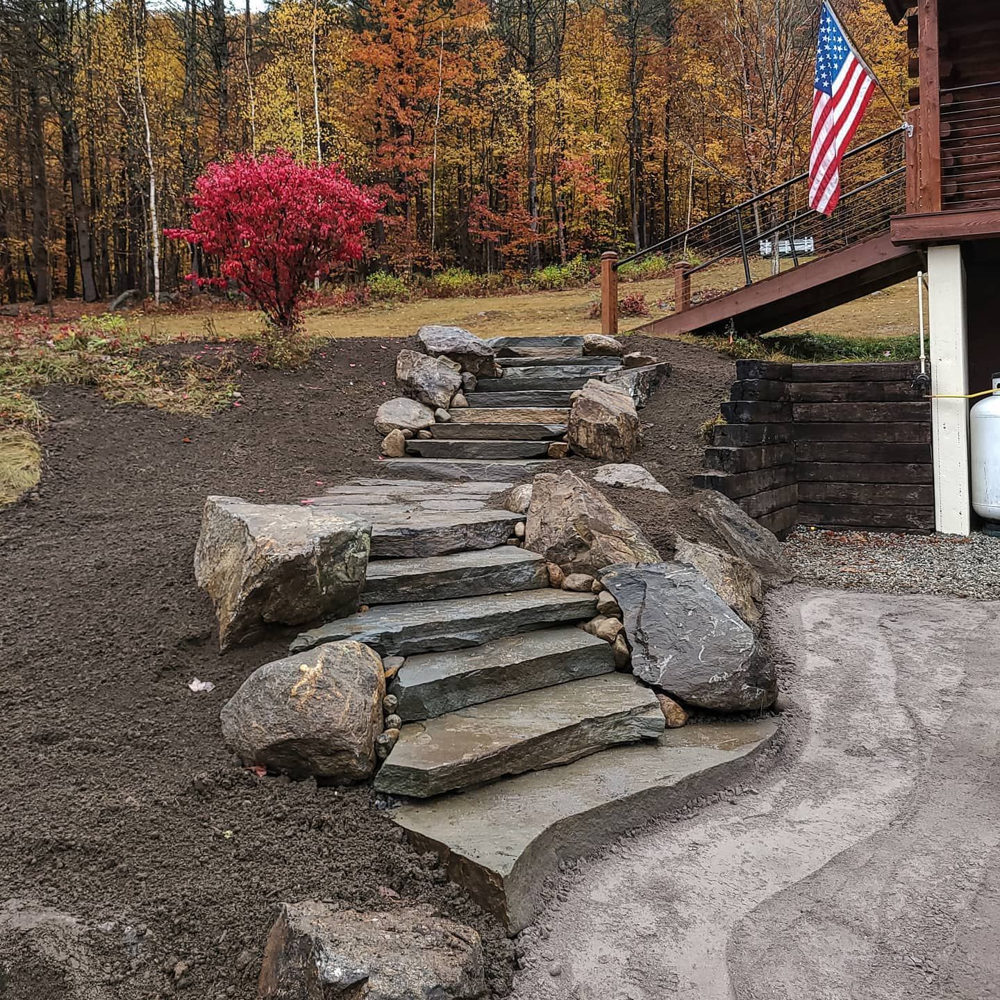 Stone steps lead up a hillside, with autumn foliage and a house in the background.