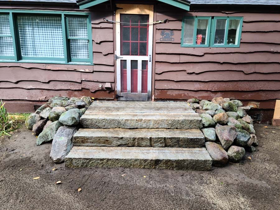 Stone steps leading to a cabin door with rock accents on either side.