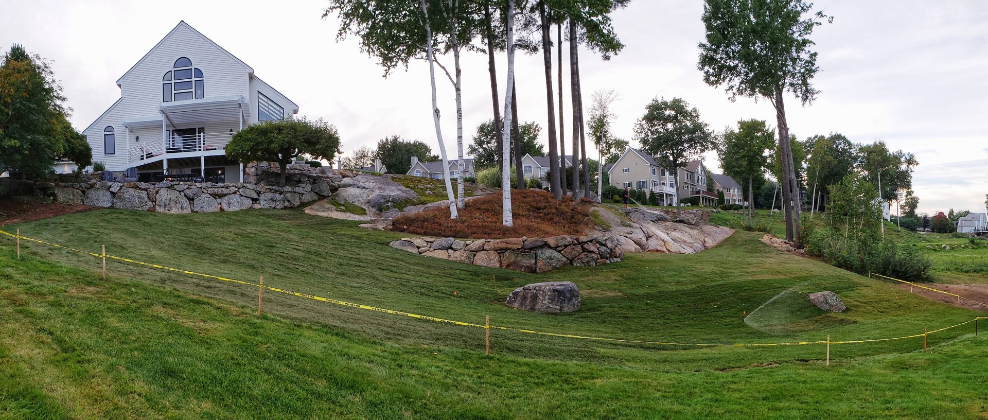 White building with trees on a grassy hill.