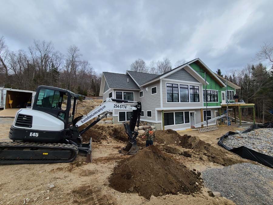 Bobcat excavator digging near a house under construction on a cloudy day.
