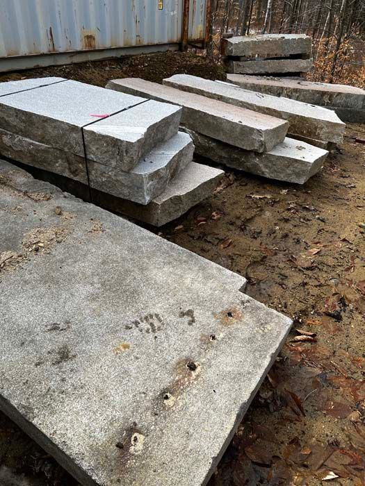 Gray granite slabs stacked outdoors.
